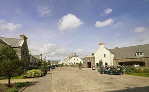 A cobblestone street lined with stone buildings, a golf cart, and a few people.