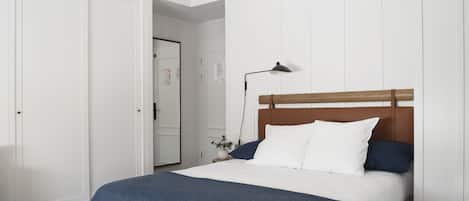 Un dormitorio con una cama, una mesita de noche, una lámpara y una puerta.