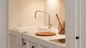A modern kitchen with white cabinetry, a wooden countertop, a sink, and a microwave. - Getaway Oostende (Ostend)