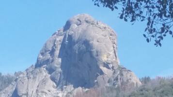 A large rock formation with sparse vegetation on a hillside.