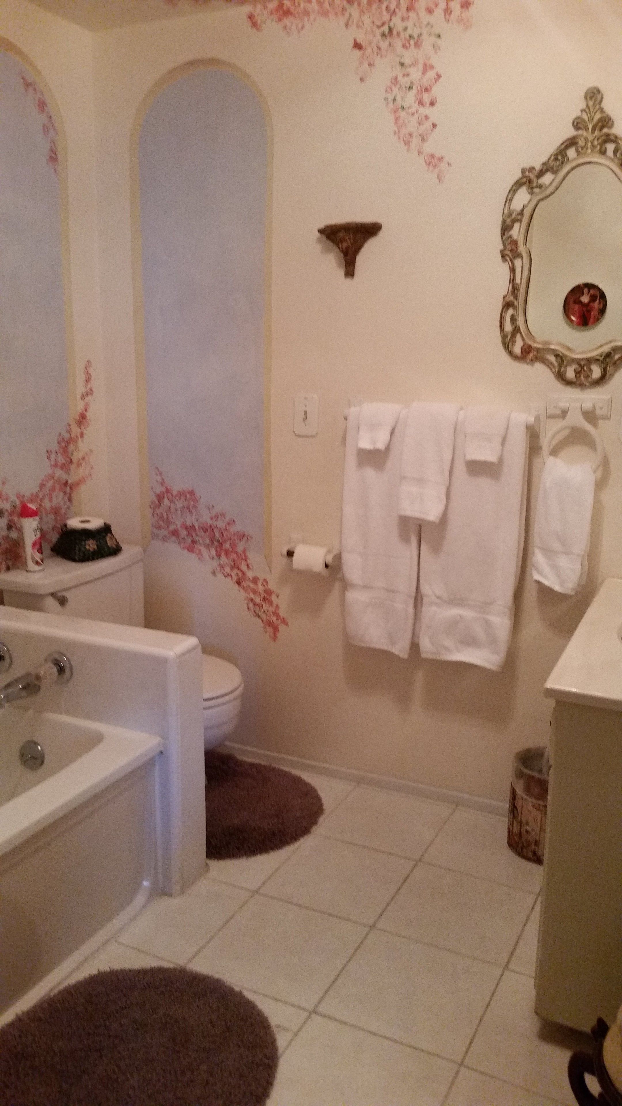 A bathroom with a bathtub, toilet, and sink. There are towels hanging on the wall and a mirror above the sink.