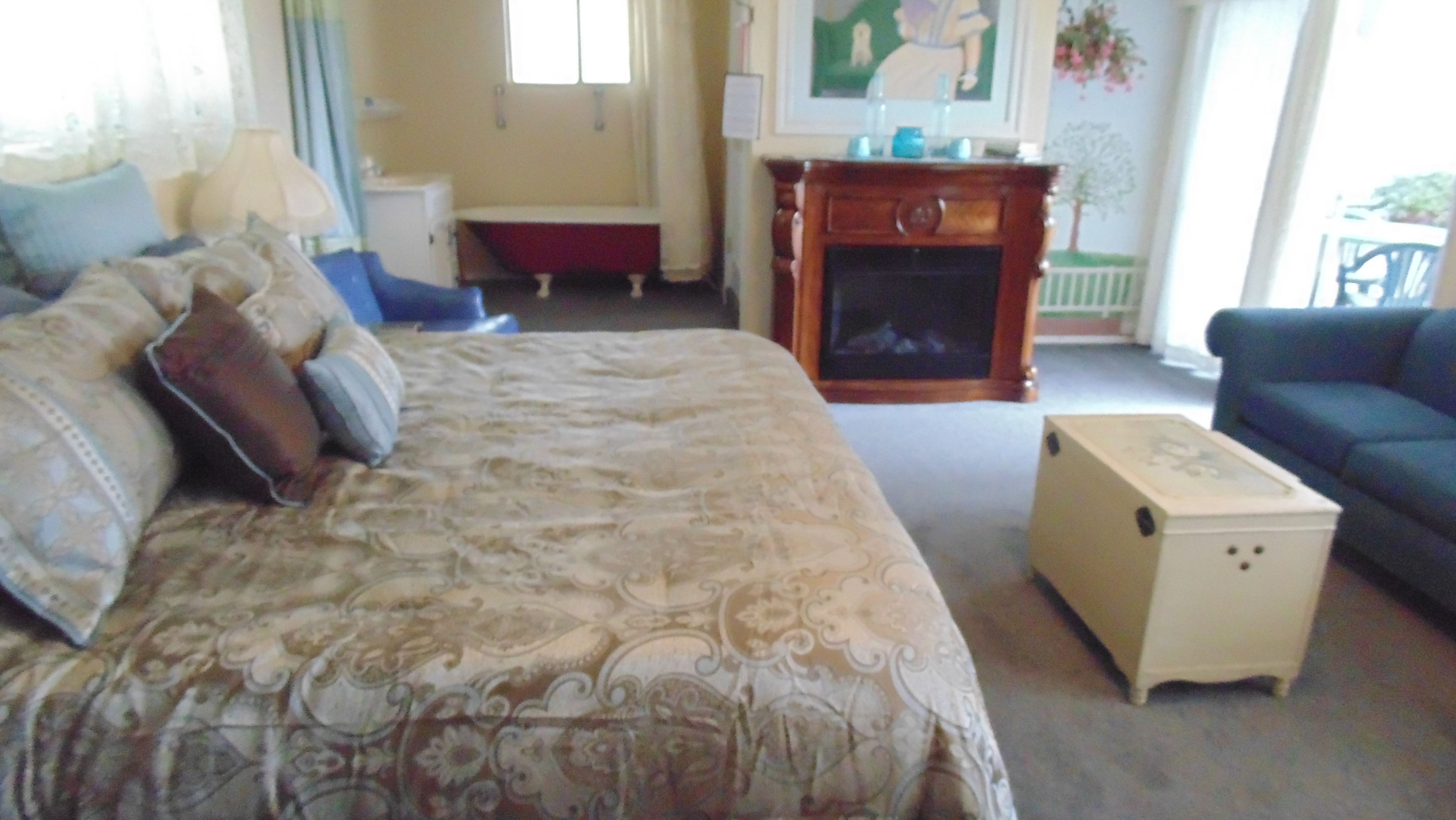 A bedroom with a large bed, a dresser, a fireplace, and a sofa.