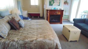 A bedroom with a large bed, a dresser, a fireplace, and a sofa.