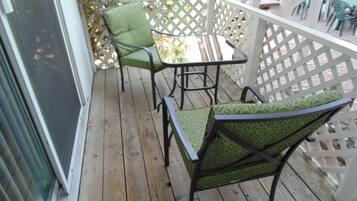 A wooden deck with two green patterned chairs and a small table.