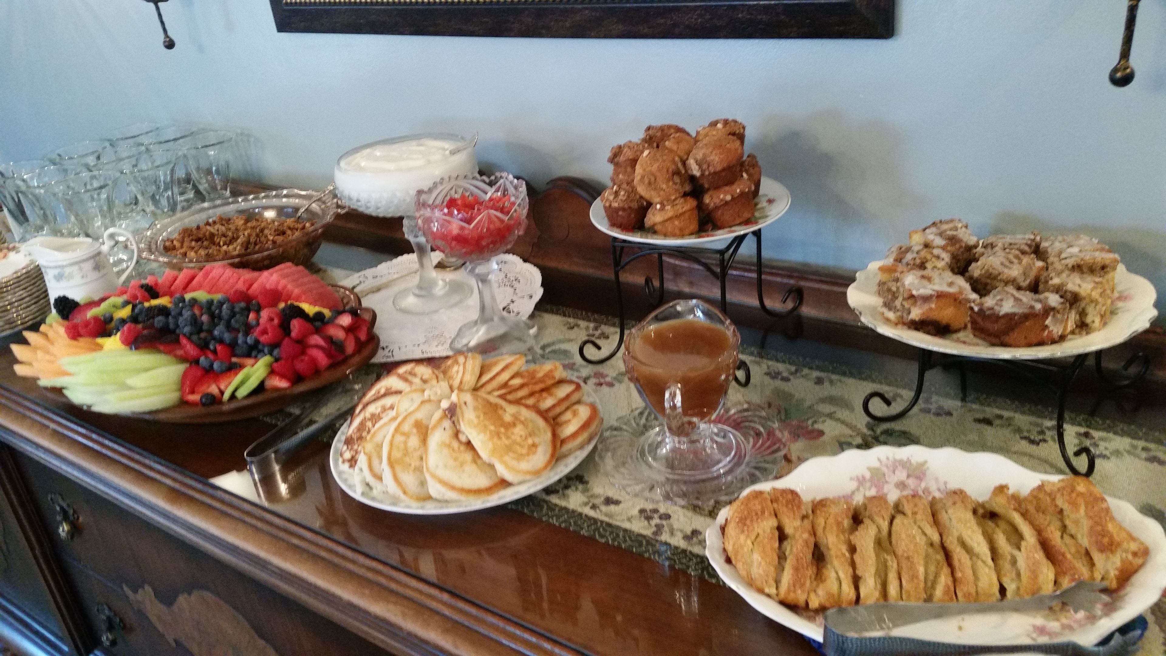Een buffet met diverse gerechten, waaronder fruit, gebak en drankjes.
