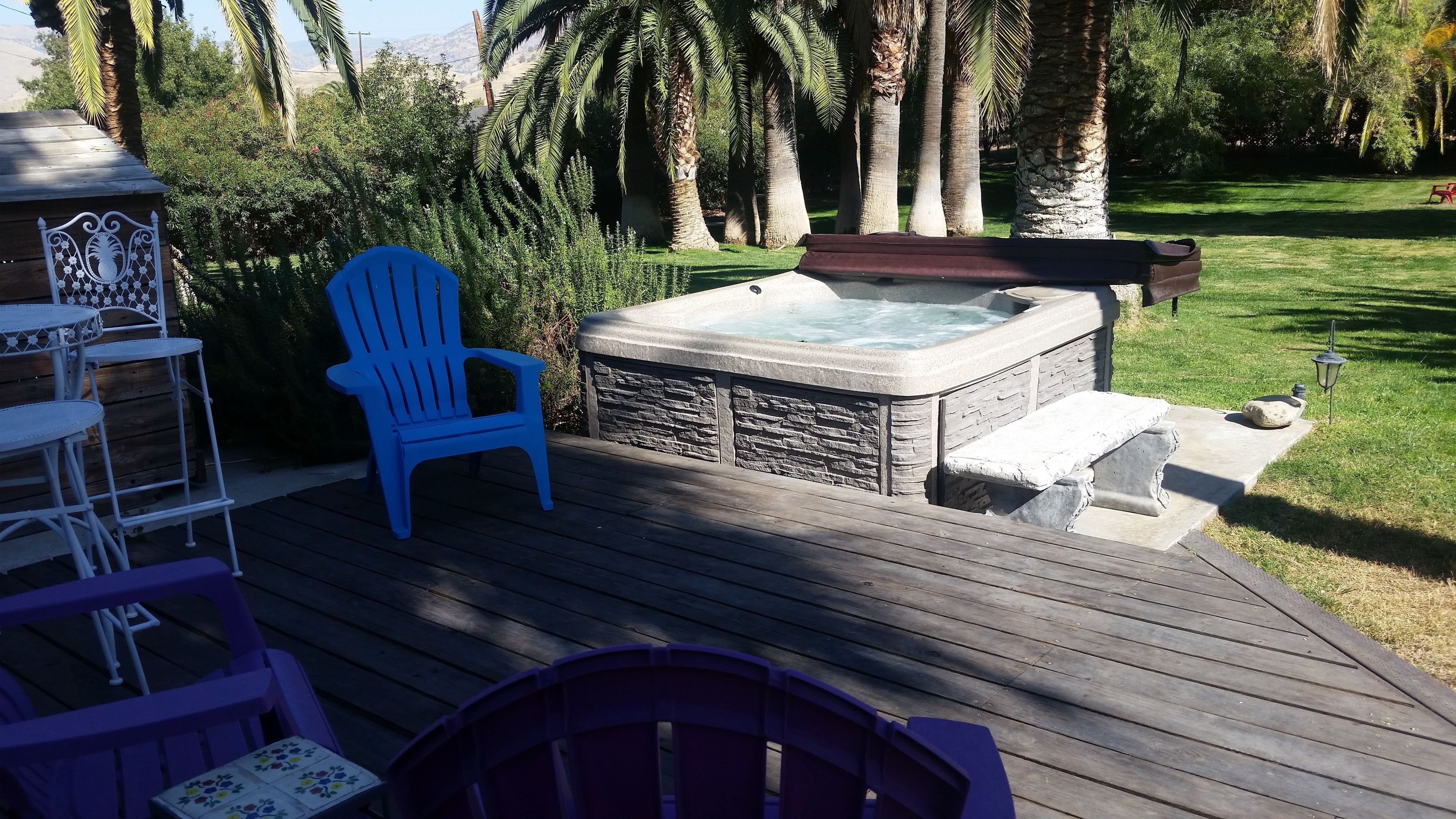 Una terraza con jacuzzi, bancos de piedra y mobiliario exterior.