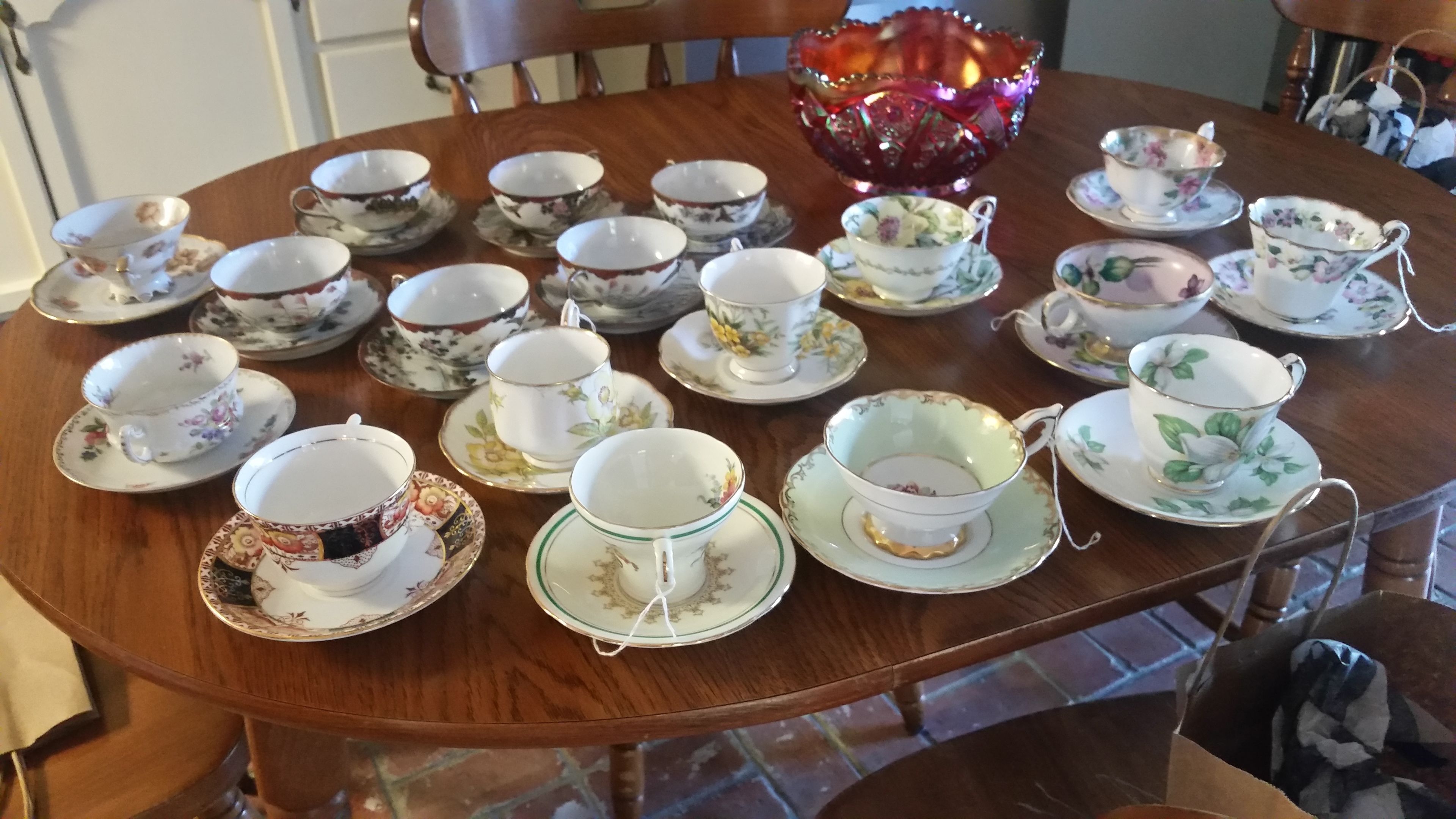 Une table à manger avec plusieurs jeux de tasses et de soucoupes à thé, un bol décoratif et une chaise.