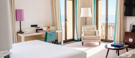 A hotel room with a bed, a desk, a chair, a small table, and a TV.