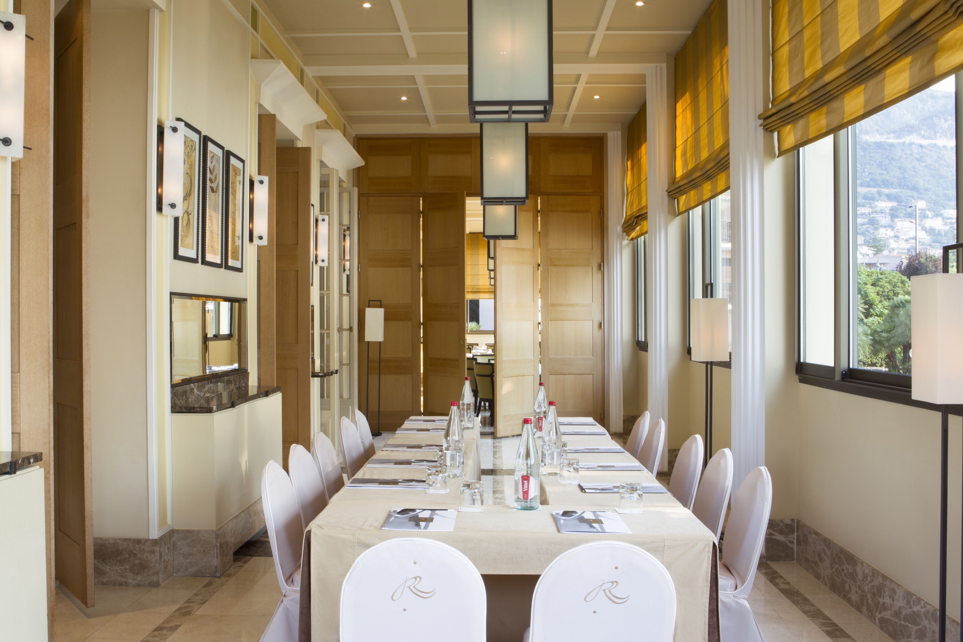 A conference room with a long table, chairs, and a view of a mountain.