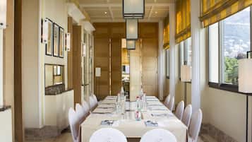 A conference room with a long table, chairs, and a view of a mountain.