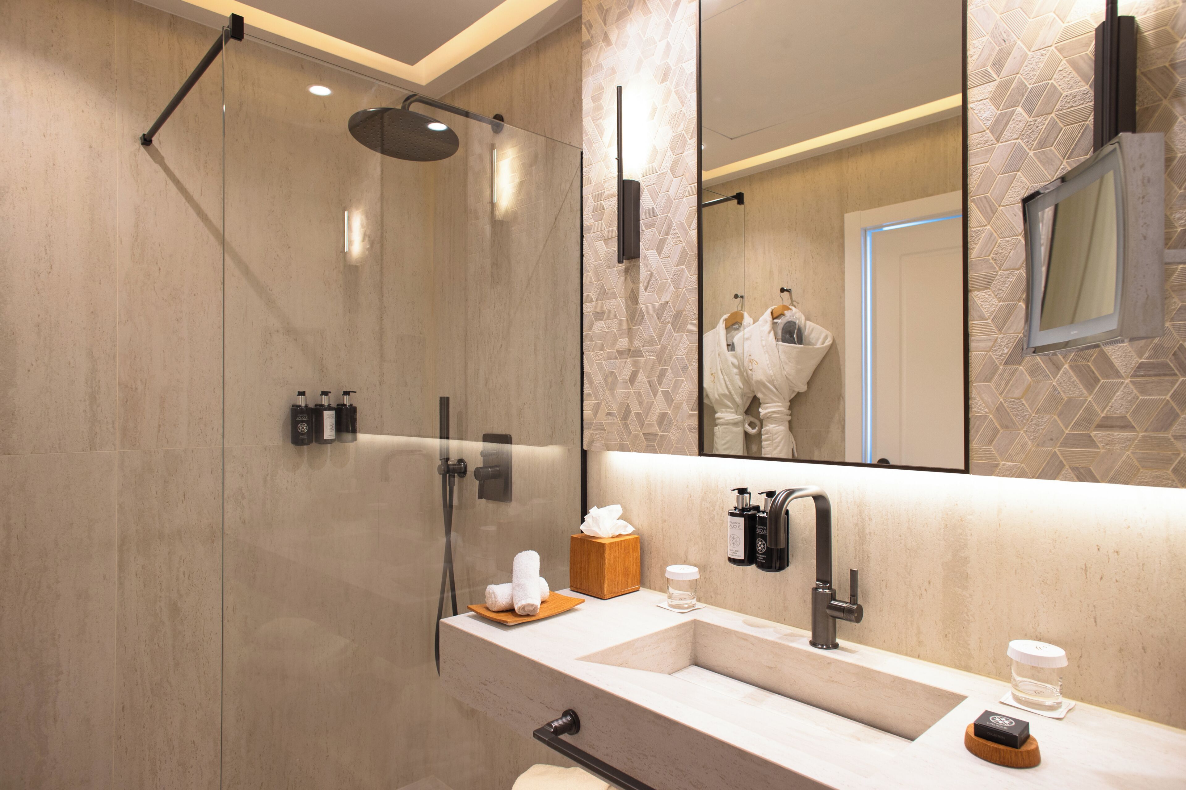 A modern bathroom with a glass-enclosed shower, a sink with a mirror, and toiletries.