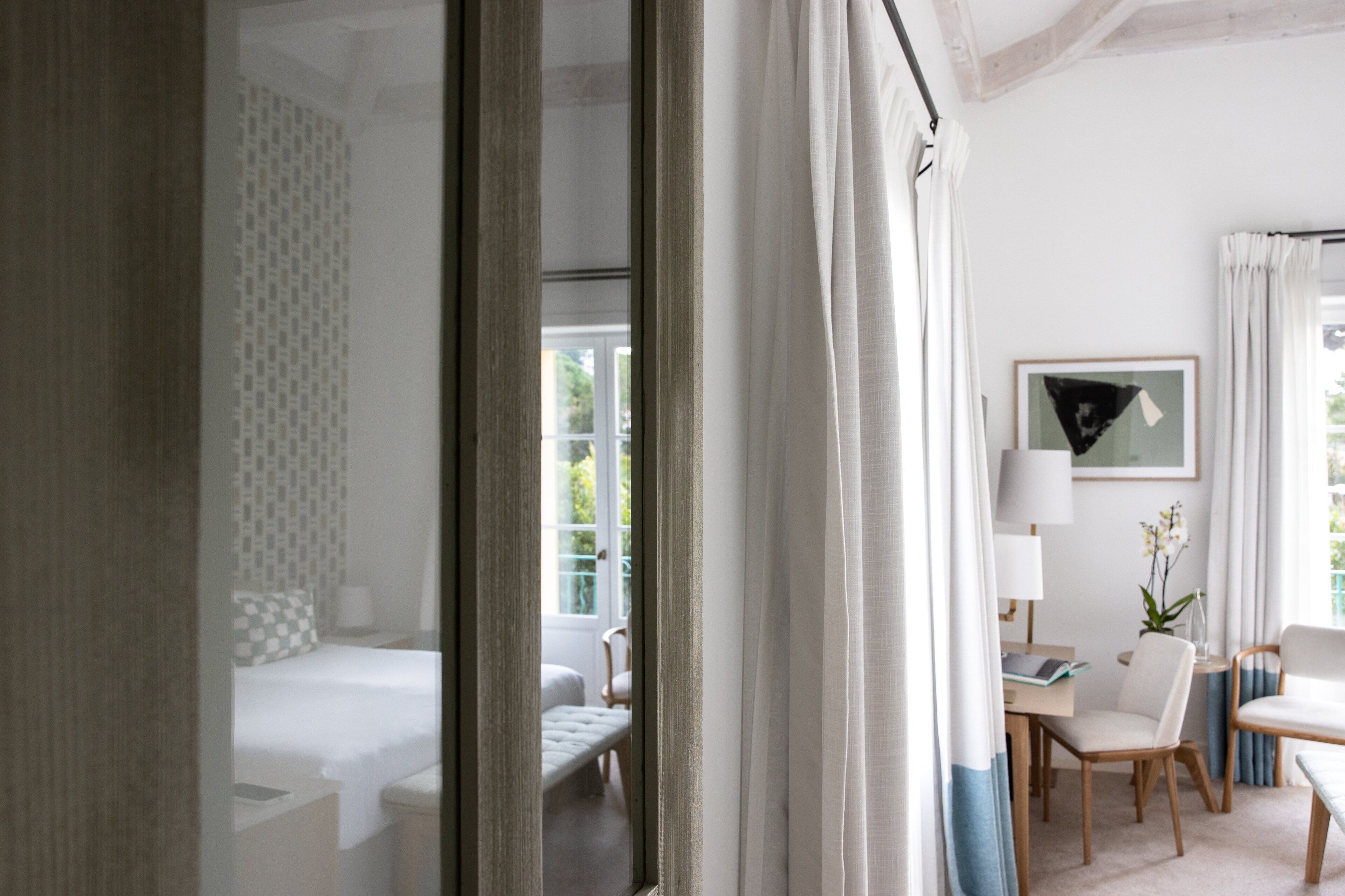 Una habitación de hotel con cama, escritorio, sillas y una ventana con cortinas.