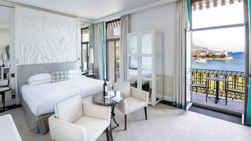 A hotel room with a bed, a desk, a chair, a balcony with a view of the sea.