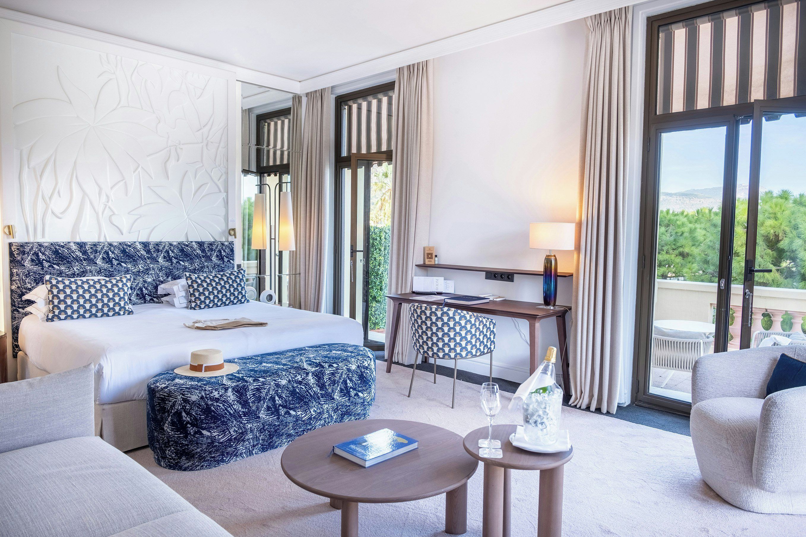 Ein Hotelzimmer mit einem großen Bett, einem Schreibtisch, einem Stuhl, einem runden Tisch und Blick ins Freie.