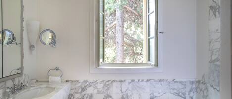 A bathroom with two sinks, a large mirror, a window, and a bathtub.