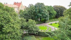 Un jardin luxuriant avec une pelouse circulaire et, au fond, un bâtiment doté d’un toit rouge.