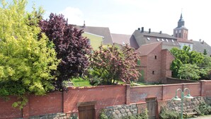 A brick wall with a stone base, a wooden door, and a bench. - Hotel am Markt (Altentreptow)