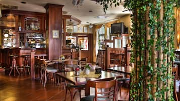 A restaurant with wooden furniture, a bar area, and a television.