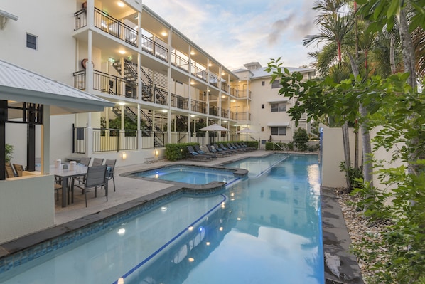 Alberca al aire libre, sombrillas en la alberca y camastros