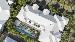 An aerial view of a modern house with a swimming pool, surrounded by lush greenery and palm trees. - Mowbray by the Sea (Port Douglas)