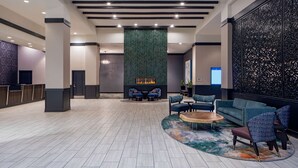 A spacious lobby with a fireplace, seating area, and decorative wall panels. - Hilton Shreveport (Shreveport)