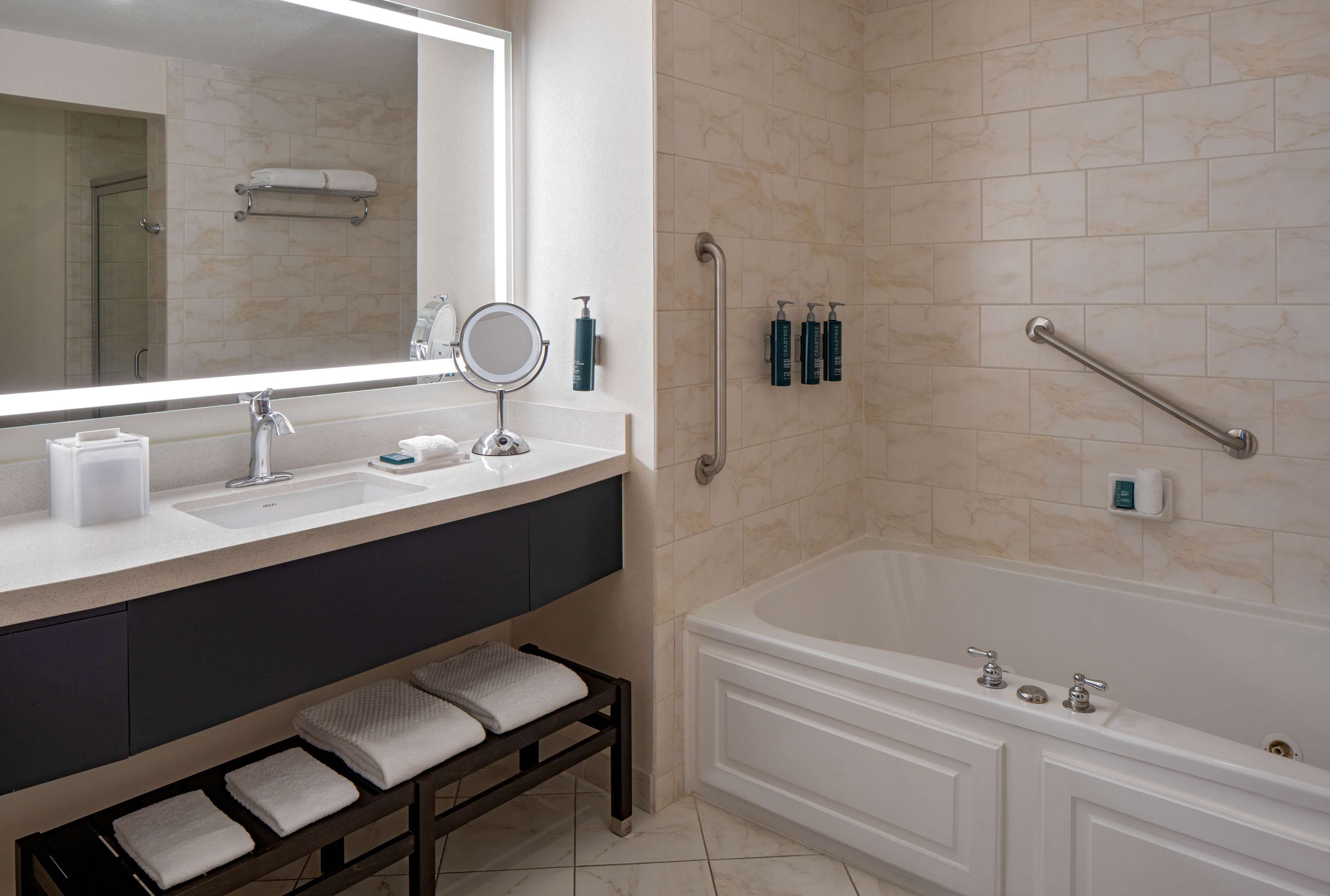 Un baño moderno con un espejo grande, un lavabo, tocador, bañera y zona de ducha.