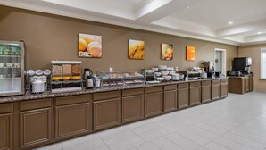 A hotel breakfast area with a self-service station, including a refrigerator, coffee makers, and various food containers. - Comfort Inn & Suites Lubbock West (Lubbock)