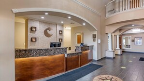 A reception area with a marble counter, wooden reception desk, and a large mirror. - Comfort Inn & Suites Lubbock West (Lubbock)