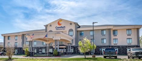 Un hotel Comfort Inn & Suites con un diseño moderno, que cuenta con una entrada central con área cubierta y varias ventanas.
