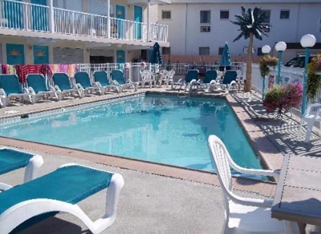 A pool area with lounge chairs and a building with balconies in the background.