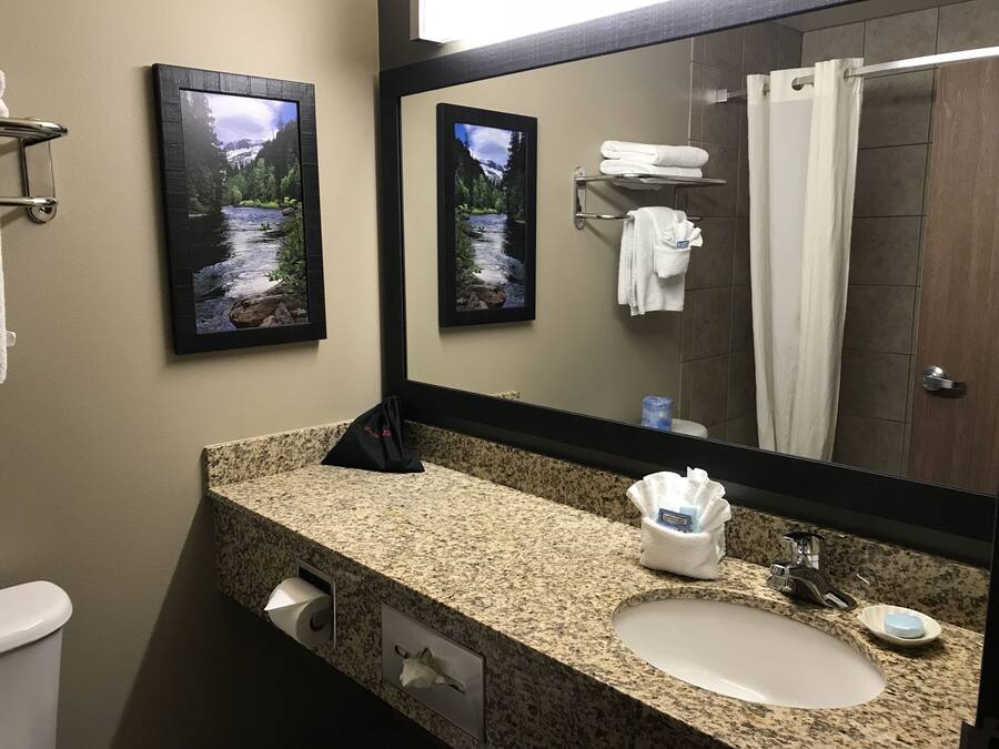 A bathroom with a granite countertop, a sink, a mirror, a towel rack, and framed pictures of a river scene.
