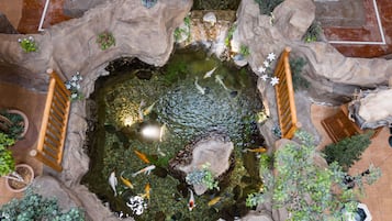 A koi pond with a wooden bridge, surrounded by rocks and plants.