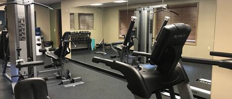 Ein Fitnessstudio mit unterschiedlichen Trainingsgeräten, darunter Laufband, Kraftgeräte und Kurzhanteln.