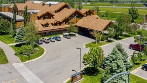 A lodge with a mountain backdrop, featuring a parking lot and a sign for the Grand Sierra Inn. - C'mon Inn Bozeman (Bozeman)
