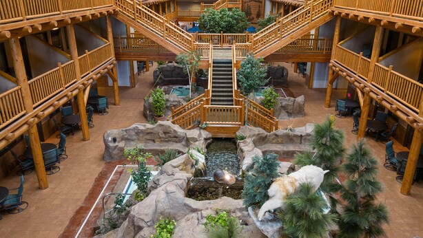A multi-level wooden interior with a central staircase, seating areas, and a small indoor water feature. - C'mon Inn Bozeman (Bozeman)