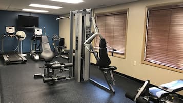 A gym with treadmills, weight machines, and a wall-mounted TV.