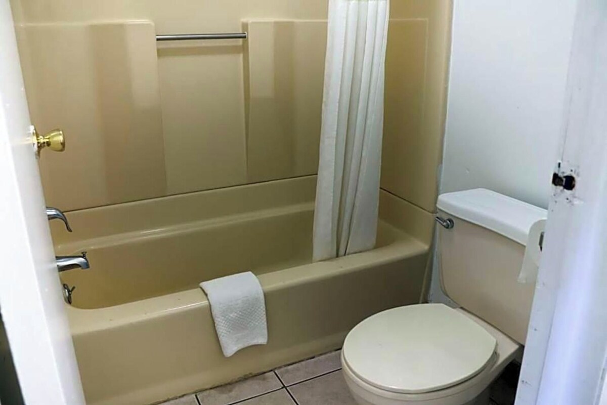 A bathroom with a bathtub, toilet, and a towel hanging on the tub.