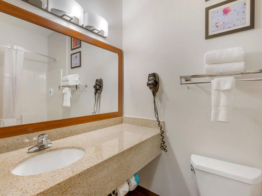 A bathroom with a sink, mirror, towel rack, and toilet.