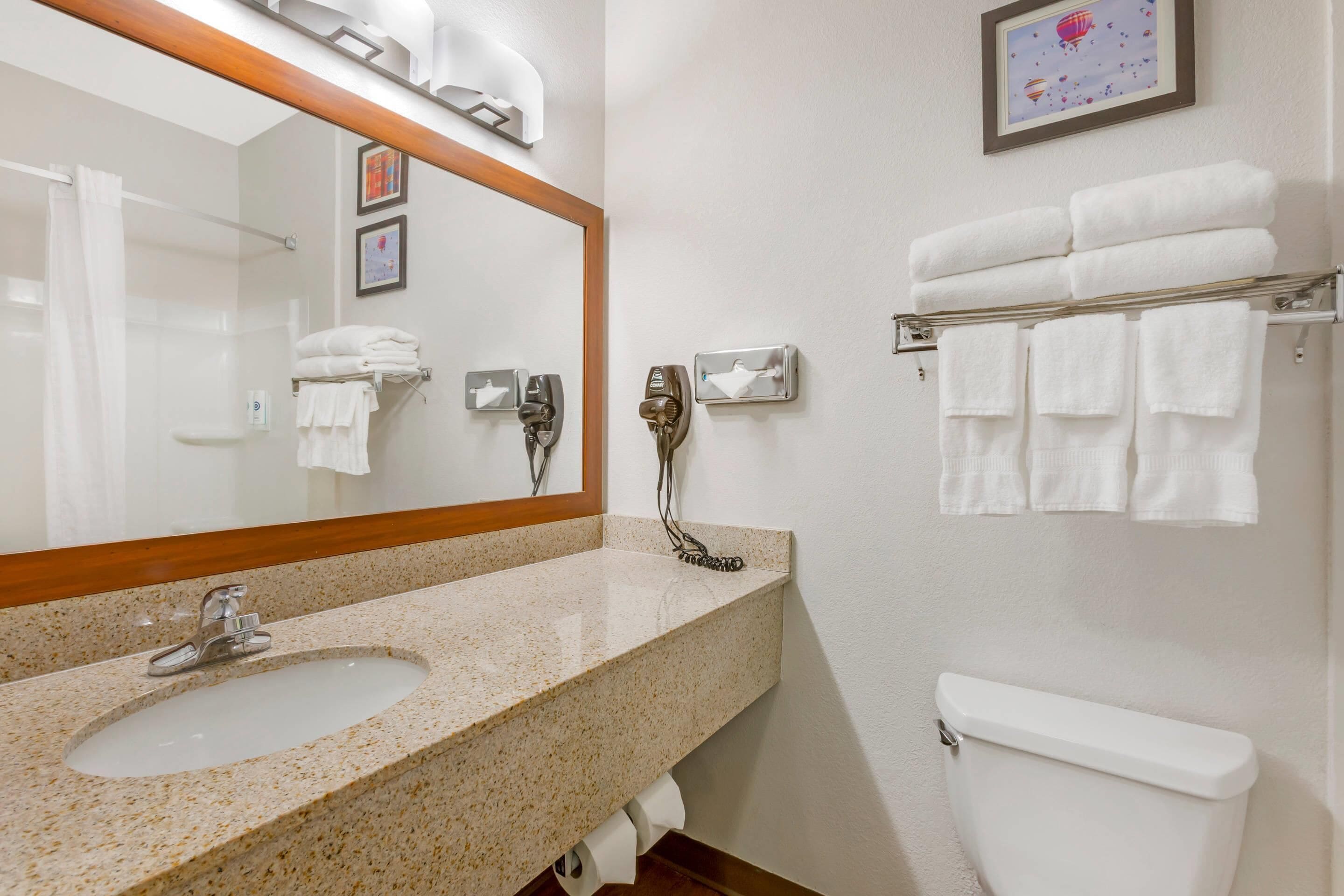 A bathroom with a sink, mirror, towel rack, and toilet.
