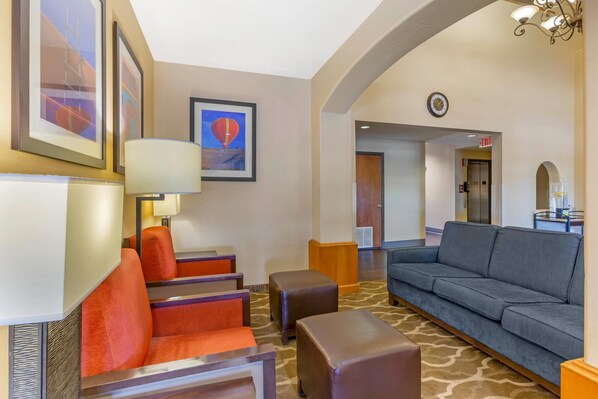 A hotel lobby with seating areas, a clock, and framed artwork on the walls.