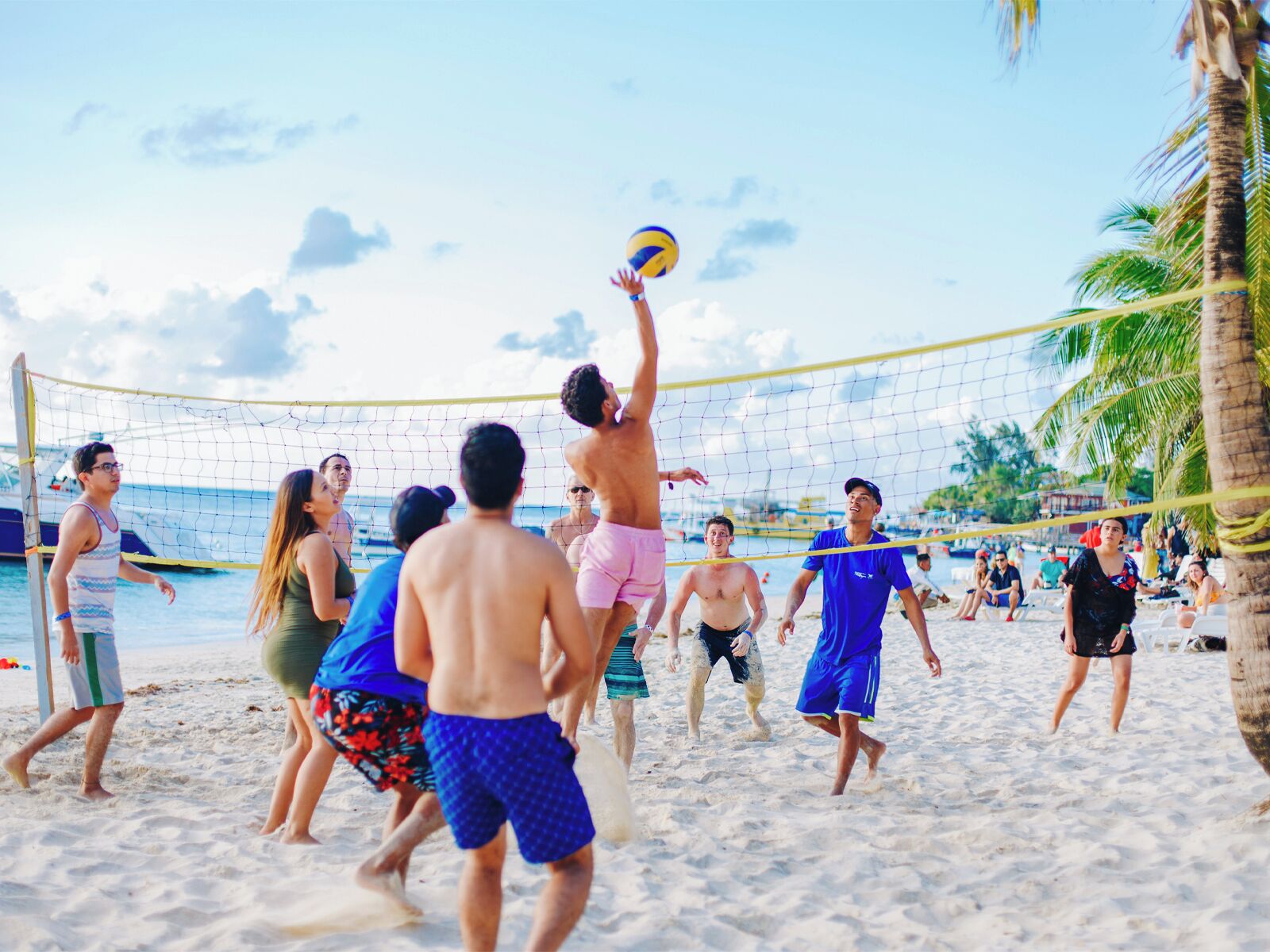 A beach volleyball game with players in various swimwear.