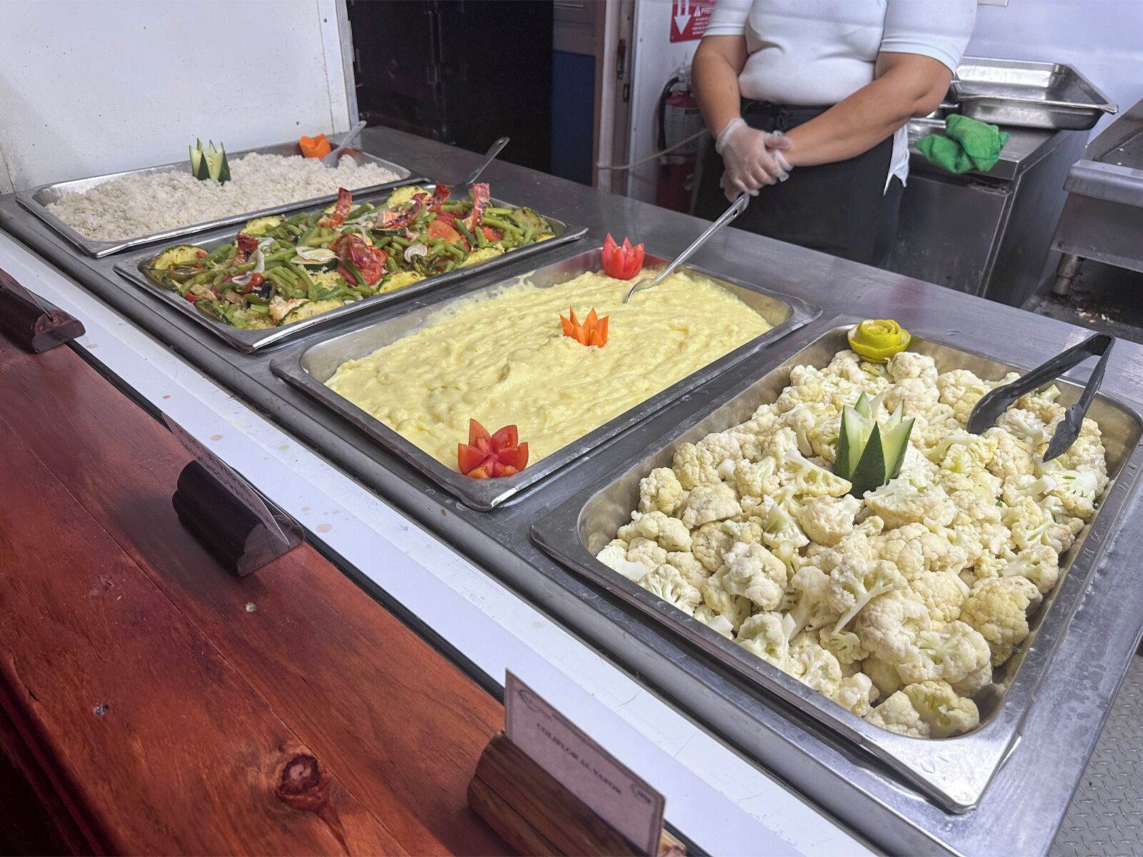 A buffet with various food items including rice, mixed vegetables, a yellow dish, and cauliflower.