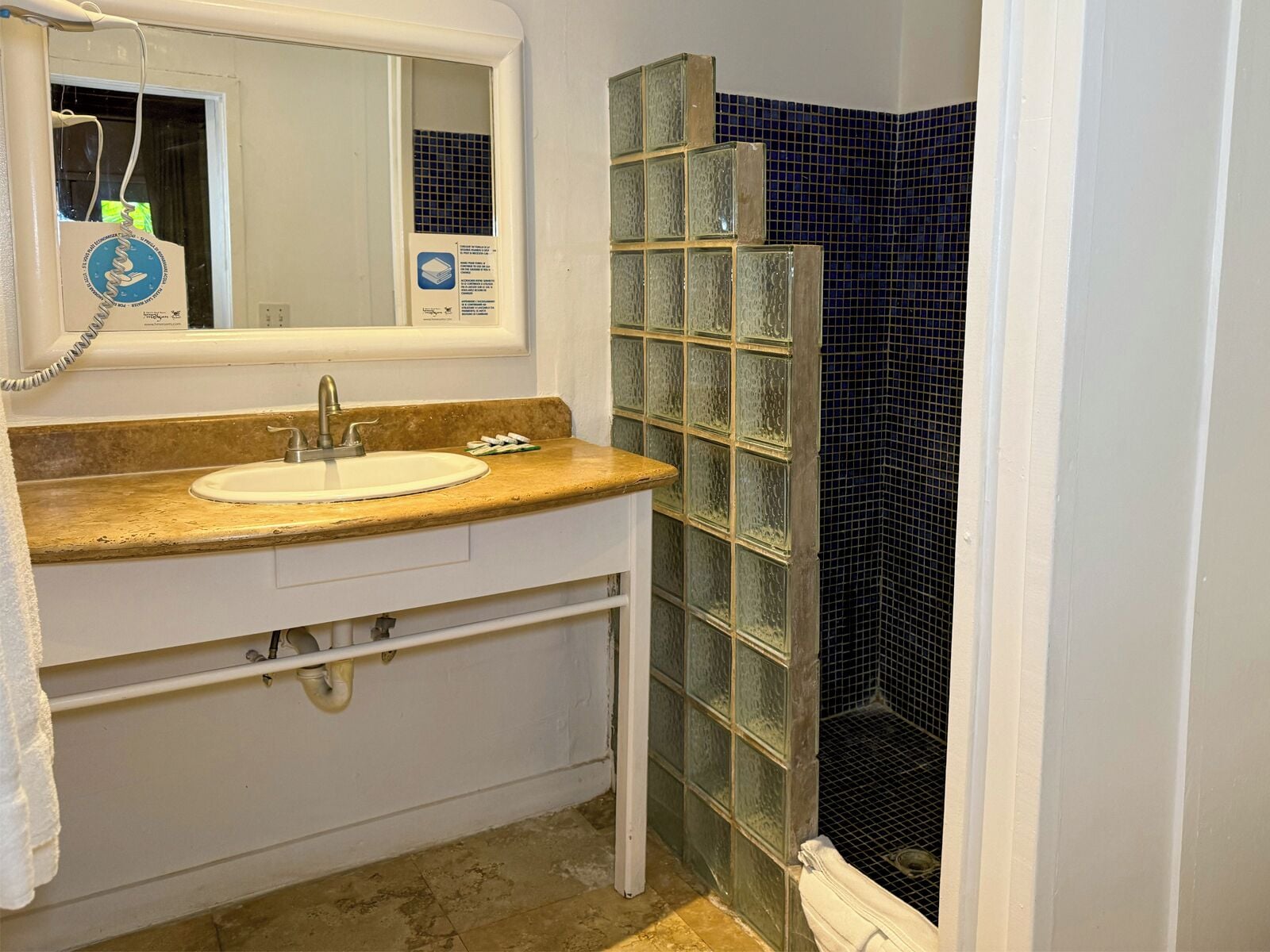 A bathroom with a sink, mirror, and a glass shower enclosure.