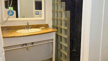 A bathroom with a sink, mirror, and a glass shower enclosure.