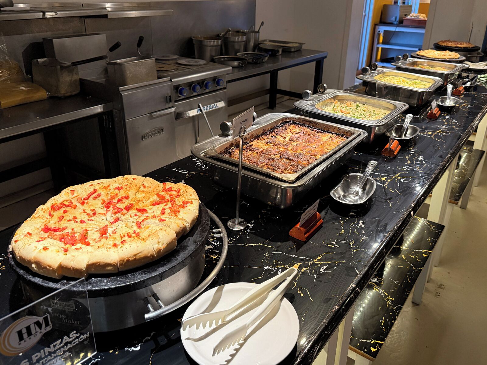 A buffet setup with various food items and a pizza on a grill.