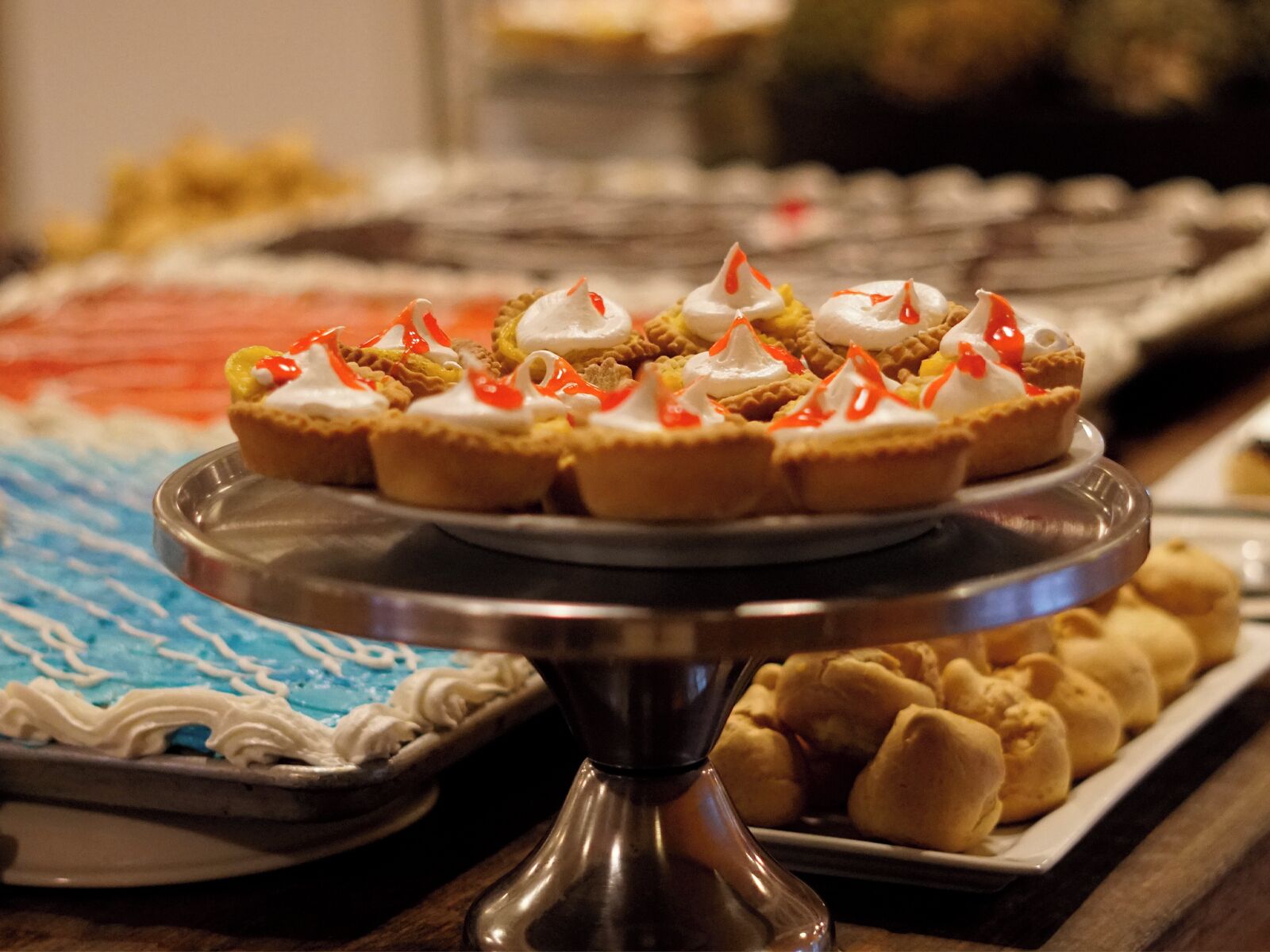 A dessert display with various pastries and a cake on a metal stand.