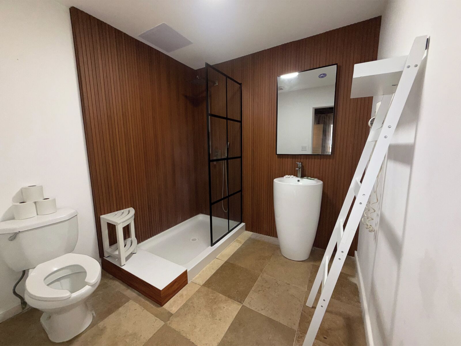 A bathroom with a toilet, a sink, a shower, and a mirror.