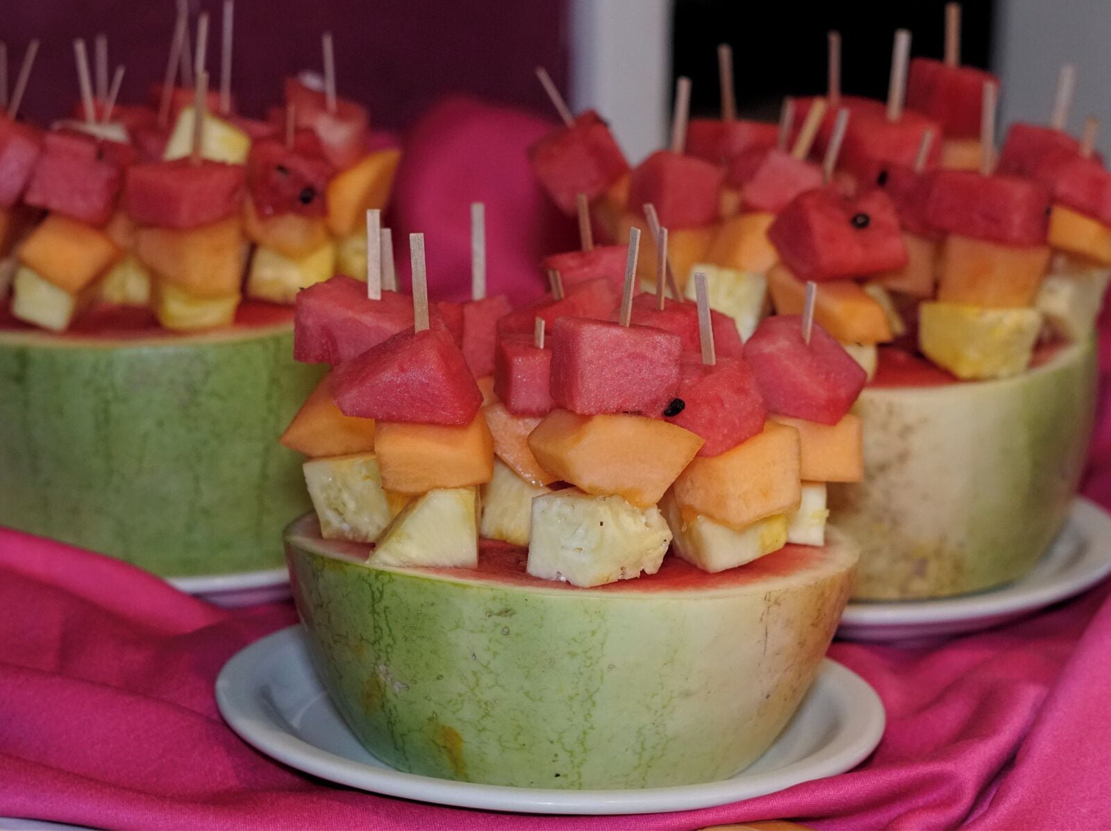 A dessert consisting of fruit skewers on top of a green bowl.