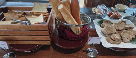 Un buffet de petit-déjeuner proposant un assortiment de pains, de sandwichs et d’œufs.