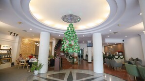 A lobby with a central staircase, a reception desk, and seating areas.